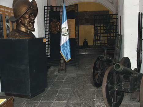 Entry hall of the Museo de Santiago, a large bust of Pedro de Alvarado looks down on two 18th century howitzers; behind are six-gauge wall guns.